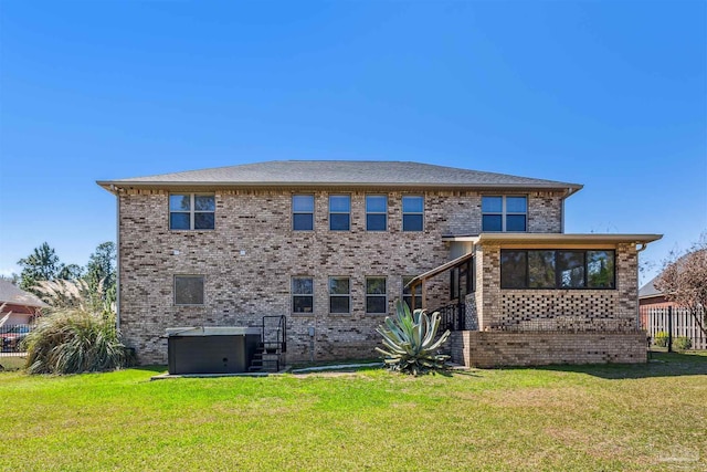 back of house with a yard, brick siding, and a jacuzzi