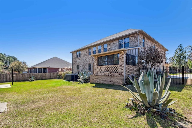 back of house with a yard, brick siding, central AC, and fence