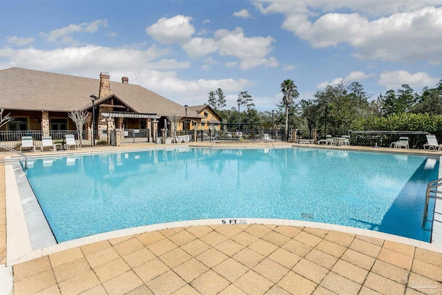 community pool with a patio and fence