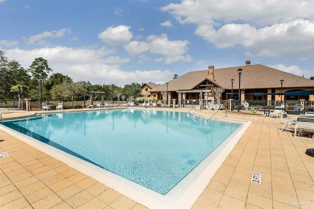 pool with a patio and fence