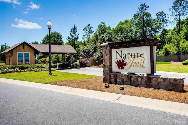 community sign with a carport, a lawn, and driveway