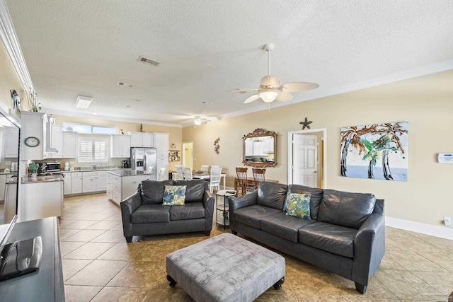 living room with light tile patterned floors, a textured ceiling, visible vents, and crown molding