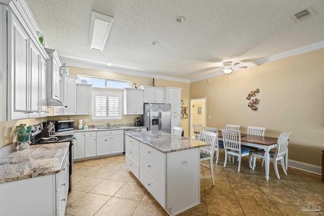 kitchen with a center island, crown molding, stainless steel appliances, visible vents, and a kitchen breakfast bar