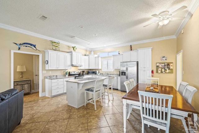 kitchen with crown molding, appliances with stainless steel finishes, white cabinets, and a center island