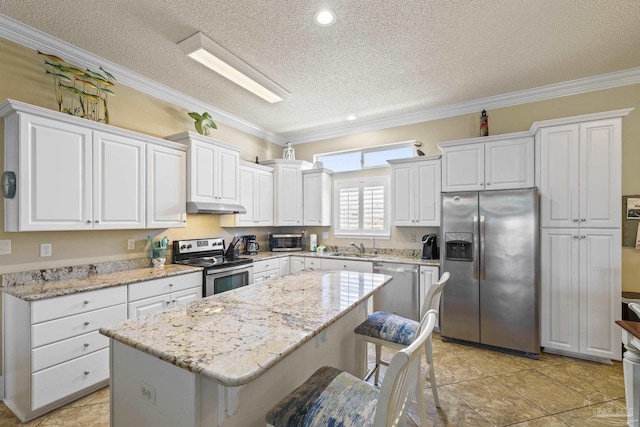 kitchen featuring appliances with stainless steel finishes, a kitchen breakfast bar, a center island, crown molding, and under cabinet range hood