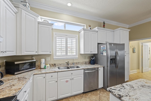 kitchen with stainless steel appliances, ornamental molding, a sink, and white cabinets