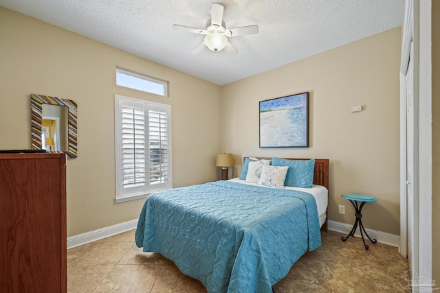 bedroom with a textured ceiling, light tile patterned floors, and baseboards