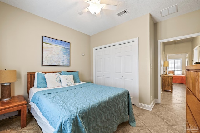 bedroom featuring light tile patterned floors, attic access, visible vents, and a closet