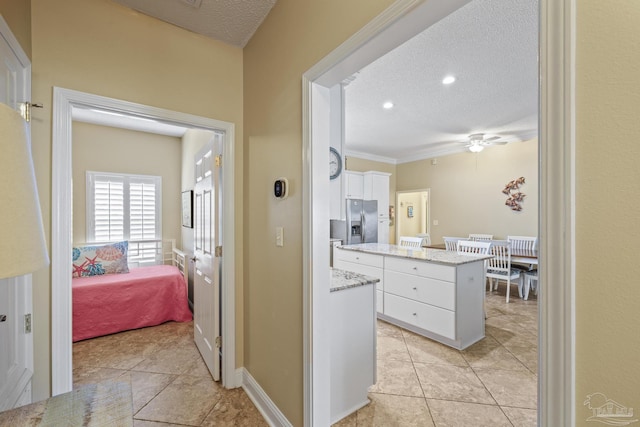 corridor featuring a textured ceiling, light tile patterned floors, and baseboards