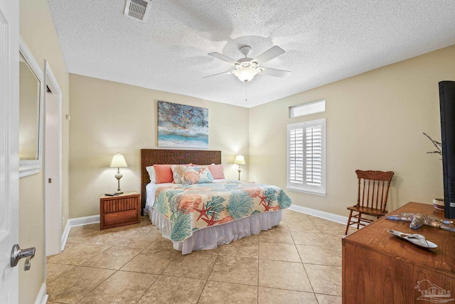 bedroom with visible vents, a textured ceiling, baseboards, and light tile patterned floors