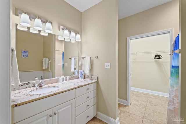 full bathroom featuring tile patterned flooring, a spacious closet, baseboards, and vanity