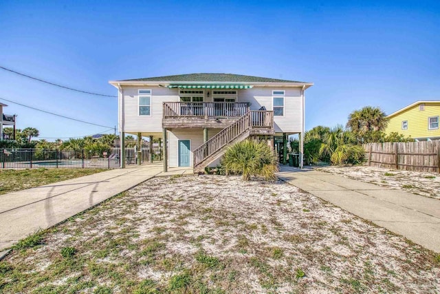 beach home with a carport, driveway, stairway, and fence