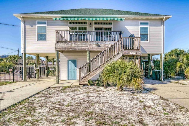 rear view of property with a carport, driveway, and stairway