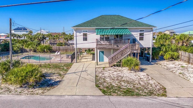 view of front of home with stairs, fence, a fenced in pool, and roof with shingles