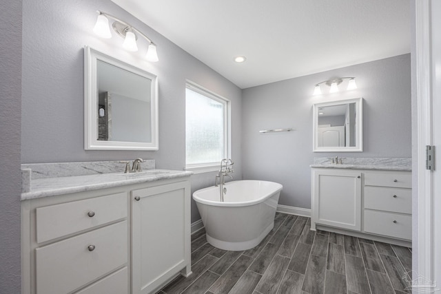 9074 Byrom Campbell Rd, Pace, FL 32571 - full bath with a freestanding tub, two vanities, baseboards, and wood finished floors