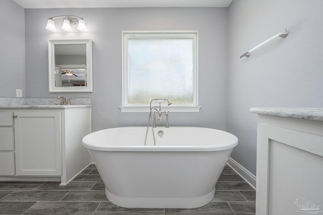9074 Byrom Campbell Rd, Pace, FL 32571 - bathroom with vanity, a soaking tub, baseboards, wood finish floors, and ceiling fan