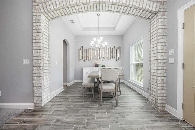9074 Byrom Campbell Rd, Pace, FL 32571 - dining area with arched walkways, a raised ceiling, wood tiled floors, and baseboards