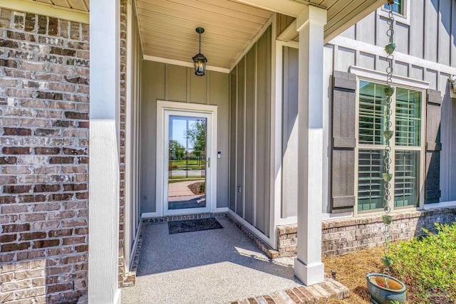 property entrance with board and batten siding and brick siding