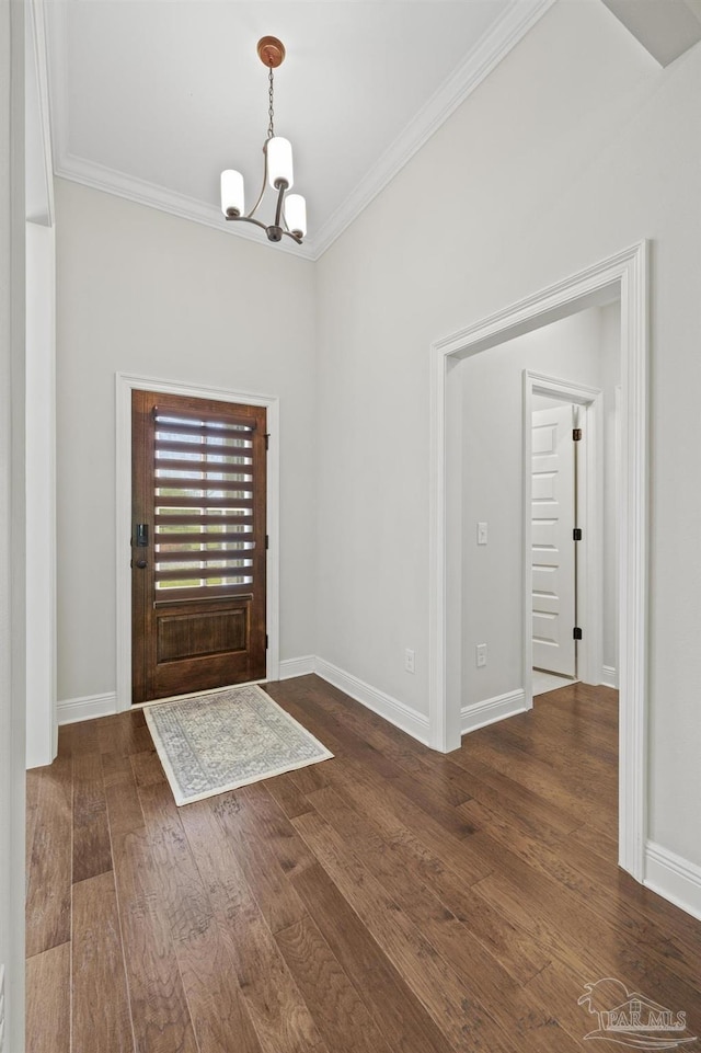 entrance foyer featuring baseboards, wood finished floors, a chandelier, and ornamental molding
