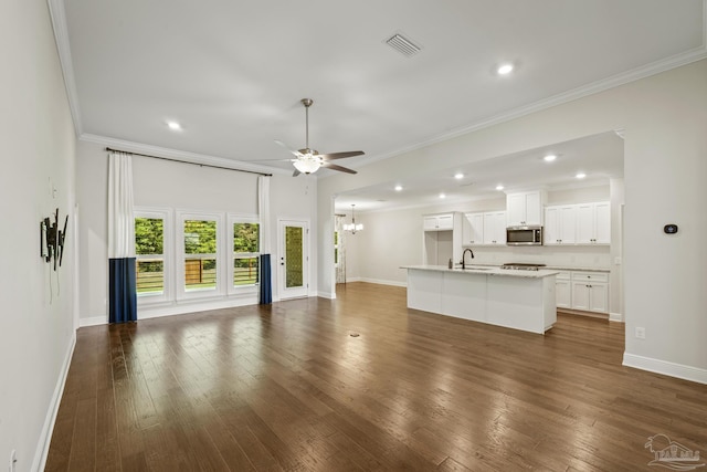 unfurnished living room with ceiling fan with notable chandelier, baseboards, ornamental molding, dark wood-type flooring, and visible vents
