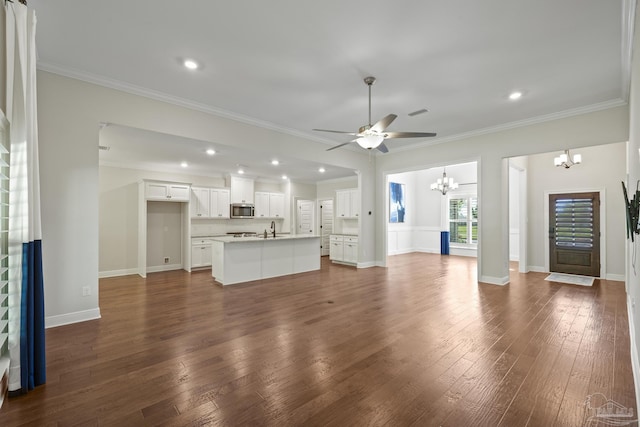 unfurnished living room featuring baseboards, ornamental molding, dark wood-type flooring, and ceiling fan with notable chandelier