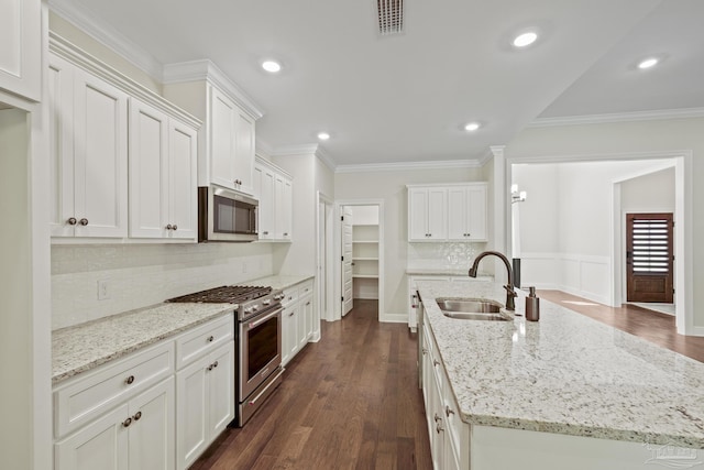 kitchen with a sink, a center island with sink, backsplash, dark wood-type flooring, and appliances with stainless steel finishes