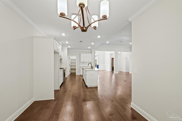 interior space featuring dark wood finished floors, an inviting chandelier, ornamental molding, and a sink