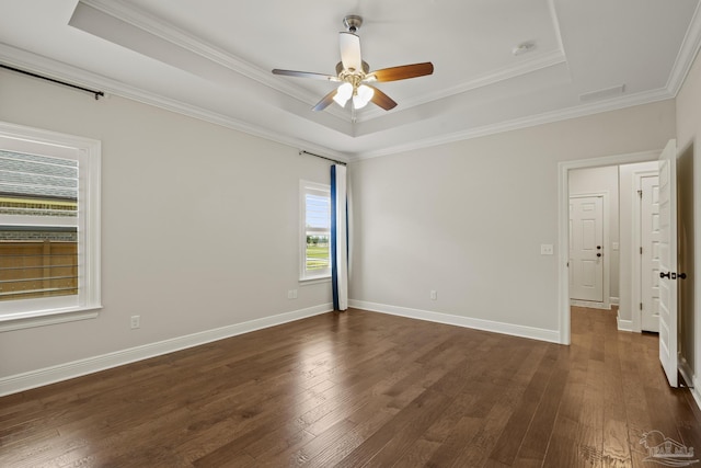 unfurnished room featuring ornamental molding, a ceiling fan, a tray ceiling, and dark wood-style floors