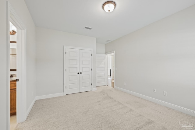 unfurnished bedroom featuring baseboards, visible vents, a closet, and light colored carpet