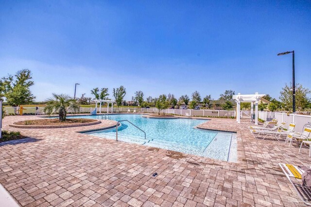 community pool with a pergola, a patio, and fence