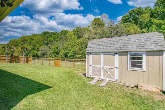 view of yard featuring a fenced backyard, a view of trees, an outbuilding, and a storage shed