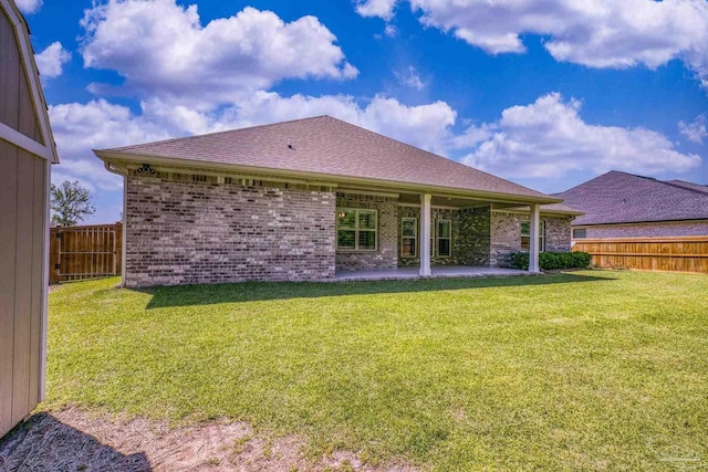 back of house featuring a fenced backyard, brick siding, a yard, and a patio