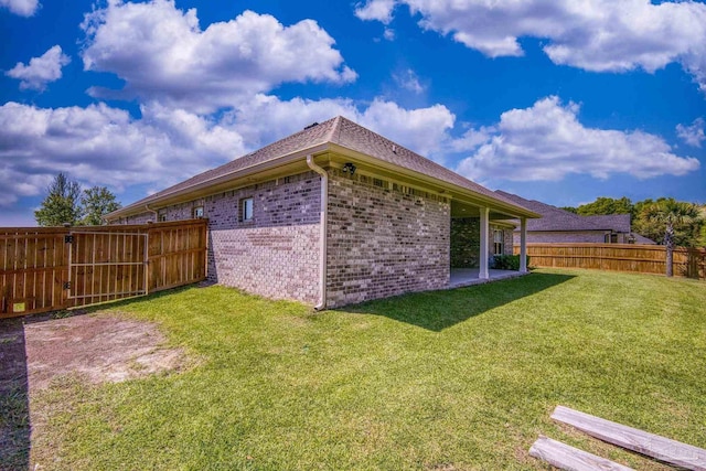 view of side of home featuring brick siding, a lawn, and a fenced backyard