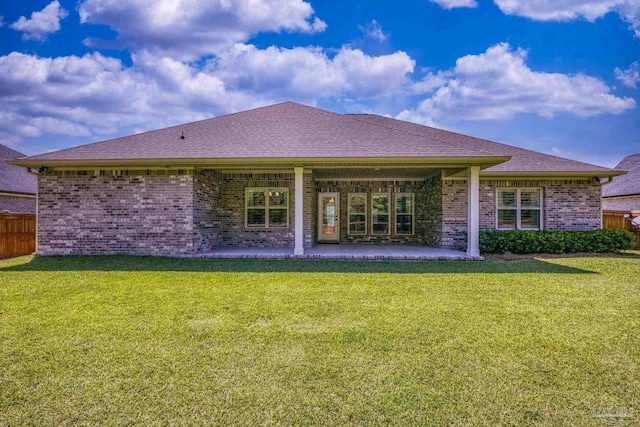 back of property featuring a lawn, brick siding, fence, and a patio area