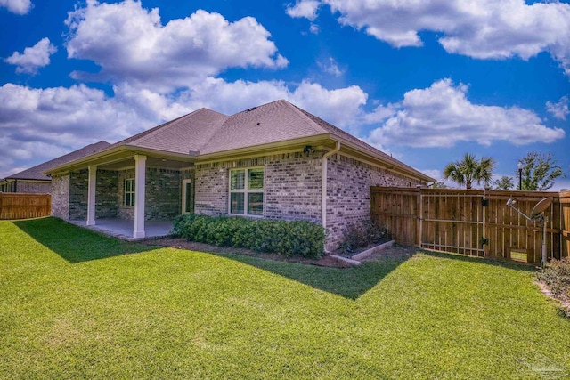back of property featuring a fenced backyard, brick siding, a patio area, a shingled roof, and a yard