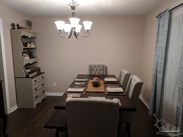 dining space featuring an inviting chandelier, a textured ceiling, and dark wood-type flooring