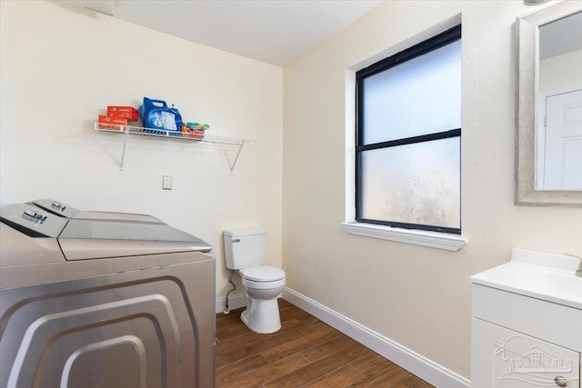 bathroom featuring a healthy amount of sunlight, toilet, wood-type flooring, and separate washer and dryer