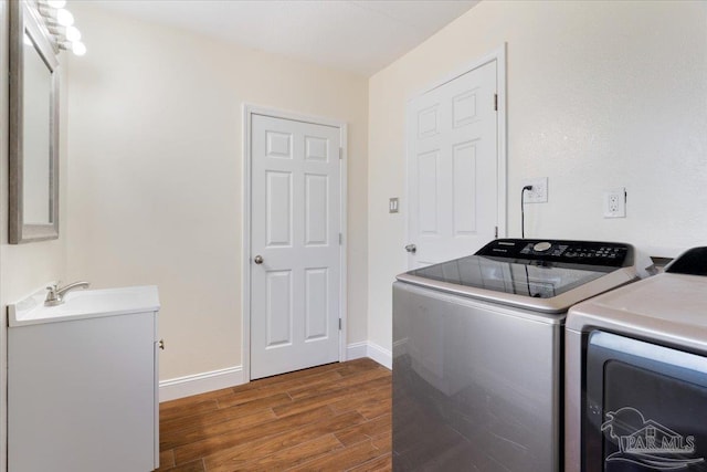 clothes washing area with independent washer and dryer, dark hardwood / wood-style flooring, and sink