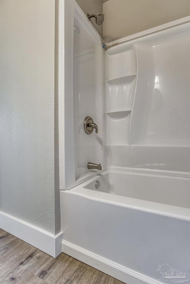 bathroom with hardwood / wood-style floors and shower / washtub combination