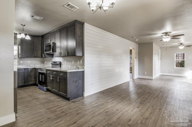 kitchen with a textured ceiling, decorative light fixtures, stainless steel appliances, and dark hardwood / wood-style floors