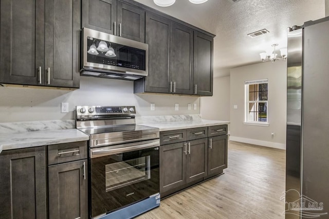 kitchen featuring dark brown cabinetry, light hardwood / wood-style flooring, and appliances with stainless steel finishes