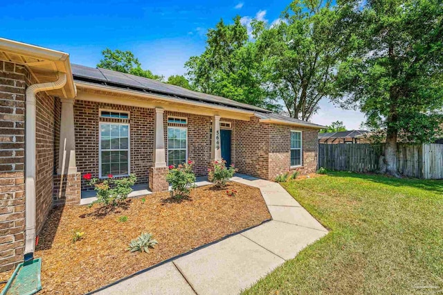 5649 Cane Syrup Cir, Pace, FL 32571 - view of front of home with brick siding, fence, solar panels, and a front lawn