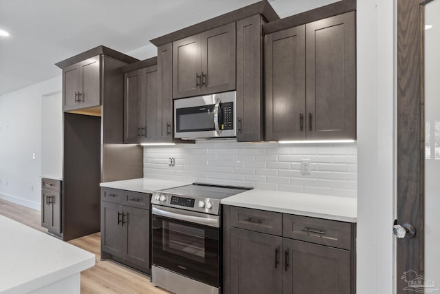 kitchen with appliances with stainless steel finishes, light hardwood / wood-style floors, decorative backsplash, and dark brown cabinets