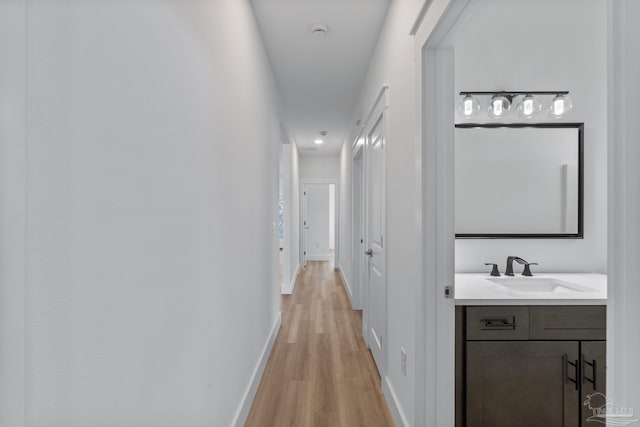 corridor with sink and light hardwood / wood-style floors