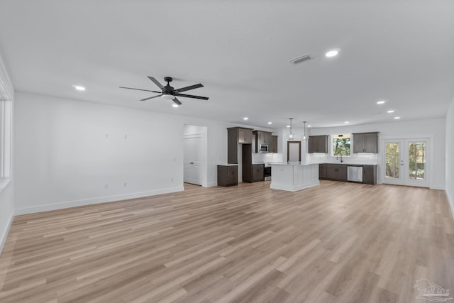 unfurnished living room with light hardwood / wood-style floors, sink, and ceiling fan