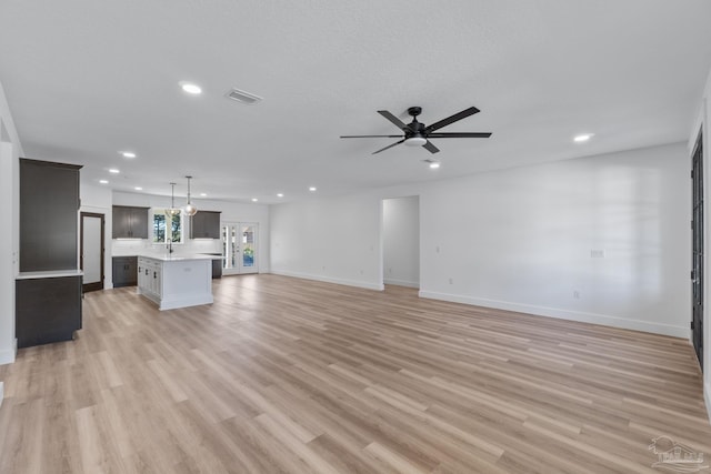 unfurnished living room with ceiling fan, light wood-type flooring, and sink