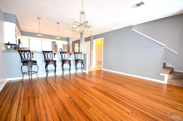 kitchen featuring a kitchen bar, stainless steel fridge, visible vents, and hardwood / wood-style floors