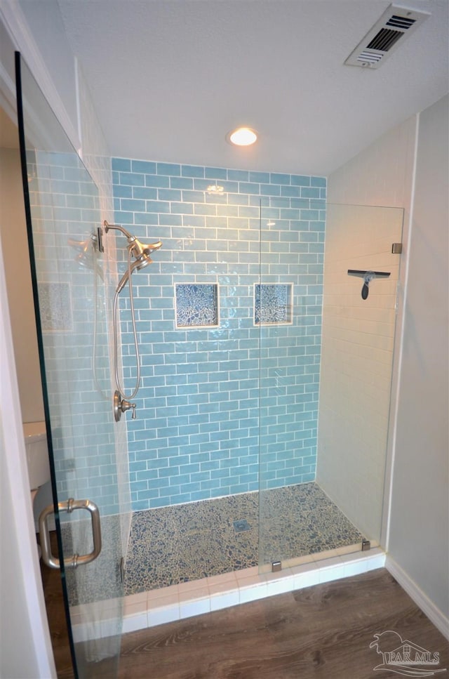 full bathroom with a stall shower, visible vents, and wood finished floors