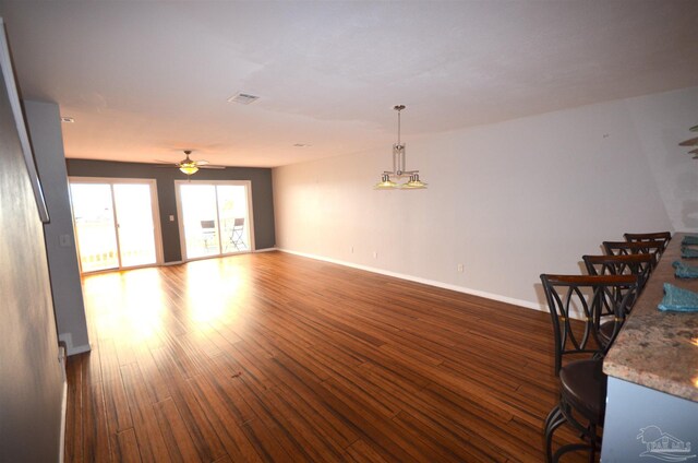 unfurnished living room featuring ceiling fan, visible vents, baseboards, and dark wood finished floors