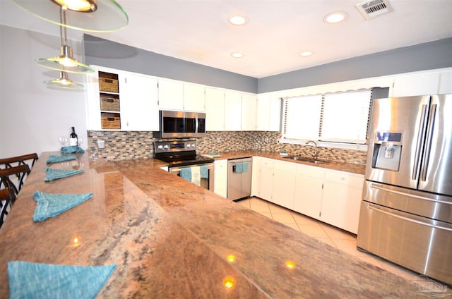 kitchen featuring visible vents, appliances with stainless steel finishes, a sink, open shelves, and backsplash